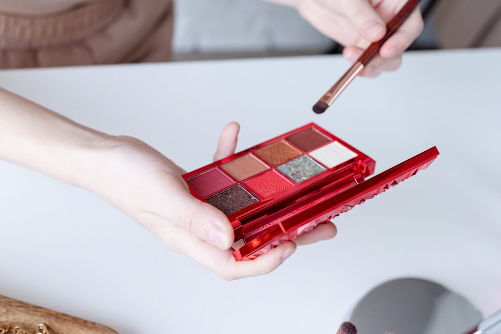 closeup of eyeshadow pallette with vivid colos in woman hand