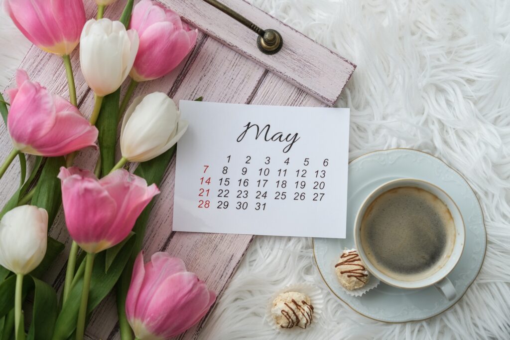 May calendar, tulips bouquet and a cup of coffee