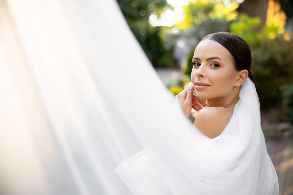 Bride posing with white veil during wedding day