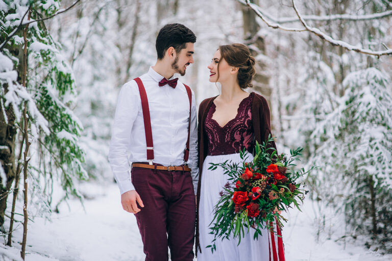 Bride and groom looking at each other in a snowy forest. Winter Wonderland Weddings.