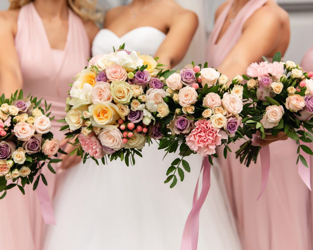 Bride and bridesmaids in pink dresses posing with bouquets at wedding day. Happy marriage and wedding party concept