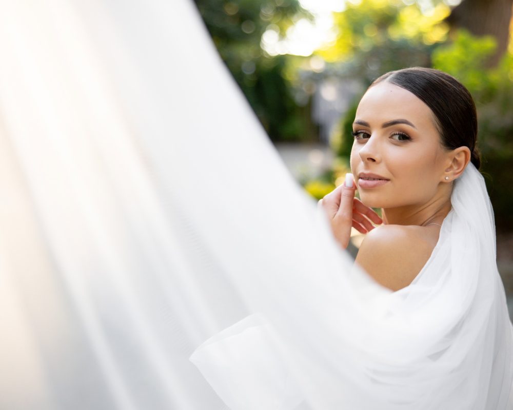 Bride posing with white veil during wedding day