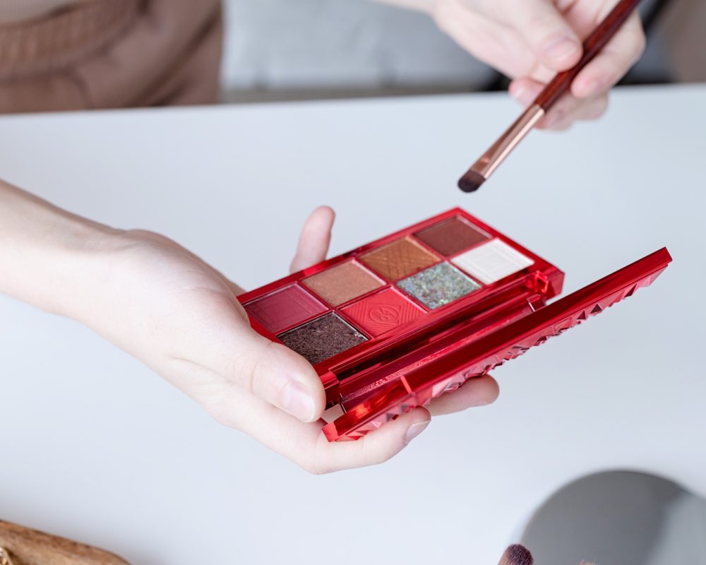 closeup of eyeshadow pallette with vivid colos in woman hand